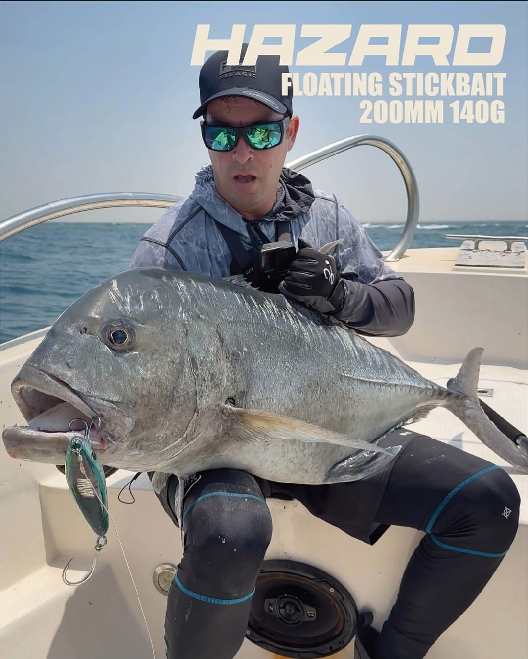 Angler holding a giant trevally with Mayday Hazard stickbait branding