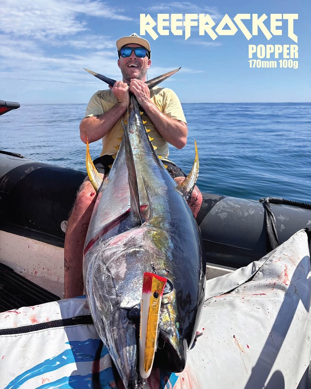 Angler holding a tuna with Mayday Reefrocket popper branding
